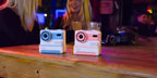 Two instant cameras on a wooden surface with a blurred background
